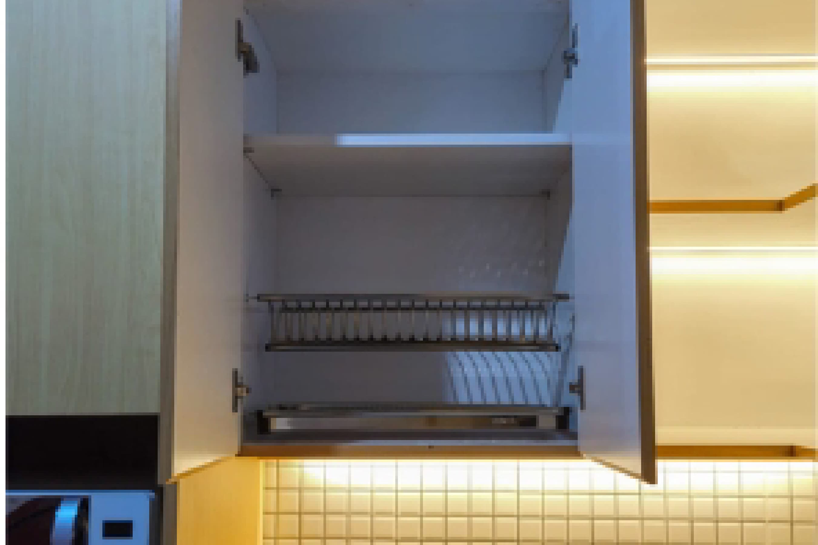 Site documentation of an open overhead cabinet with a built-in plate rack and warm under-cabinet lighting.