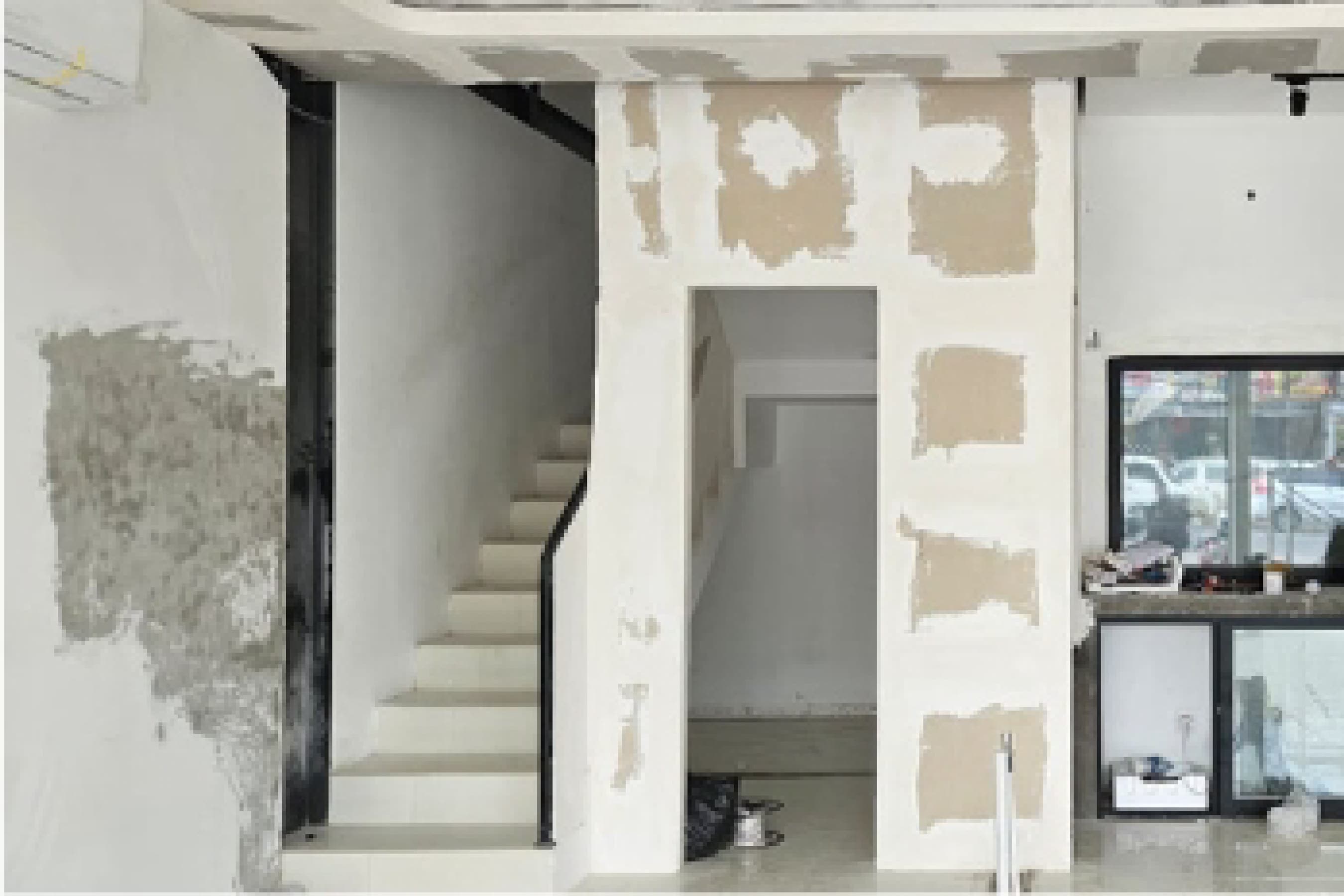 Site documentation of the stairwell mid-construction, bare plaster walls awaiting finish.