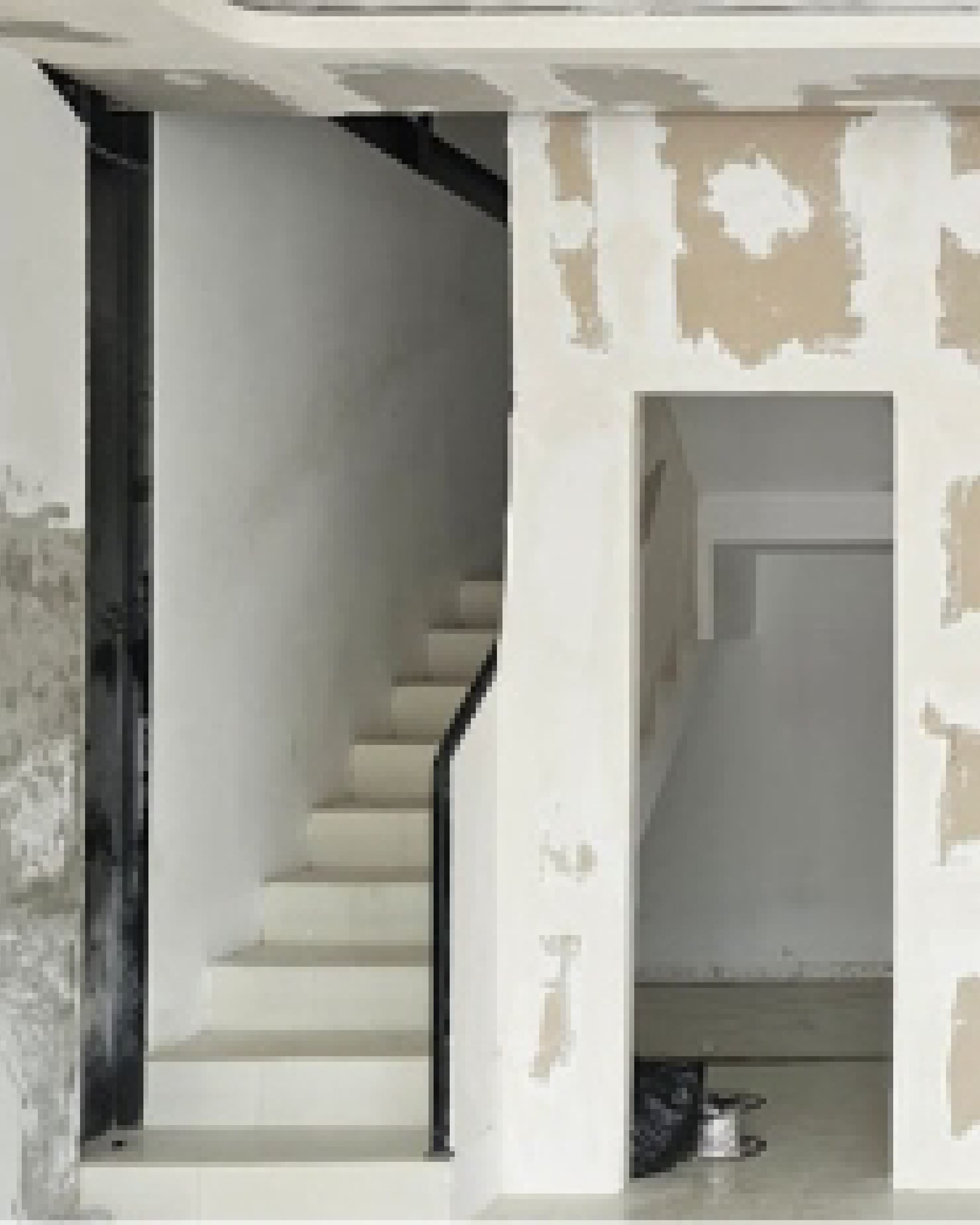 Site documentation of the stairwell mid-construction, bare plaster walls awaiting finish.