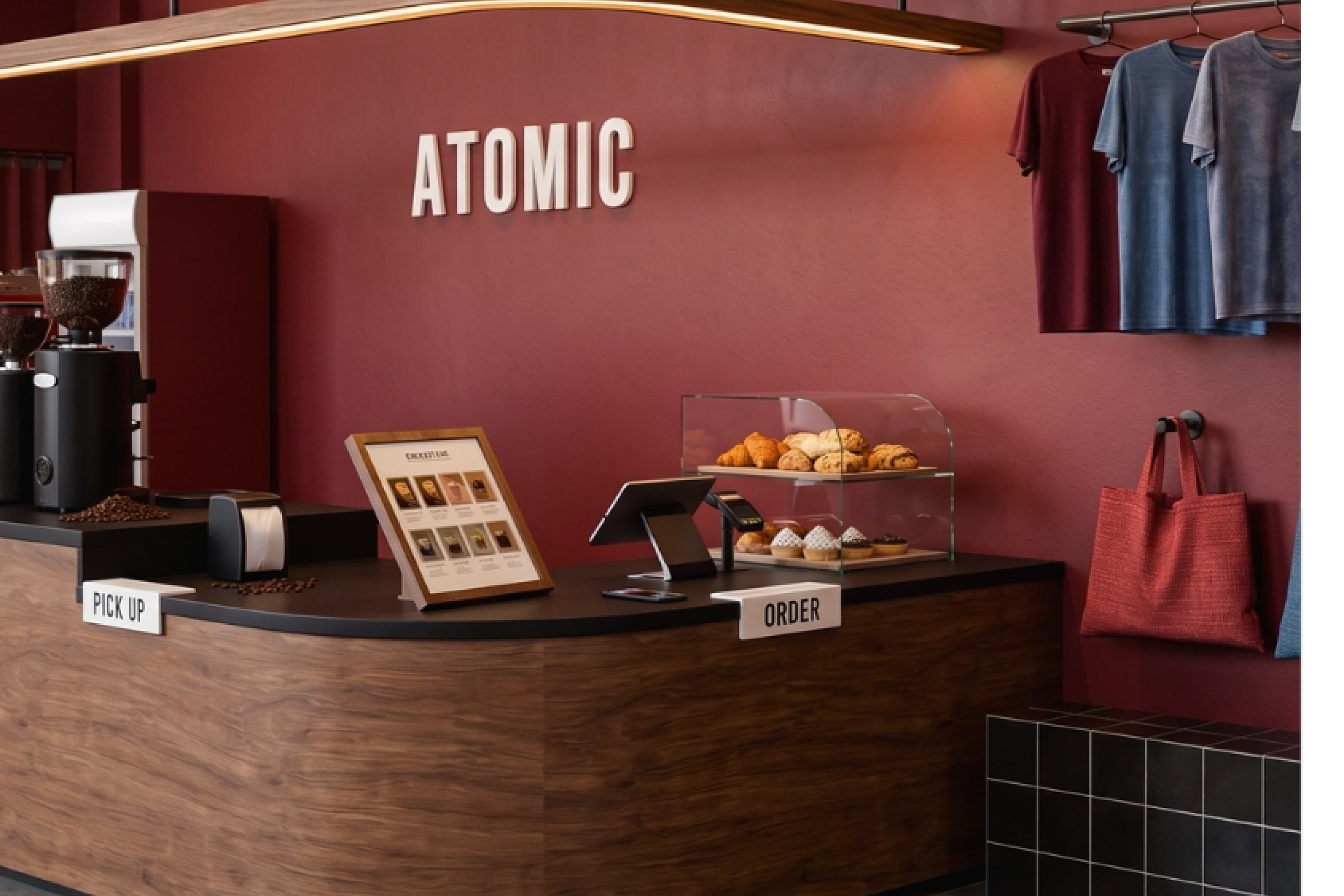Atomic Cafe counter with a bold red accent wall, illuminated signage and a pastry display.