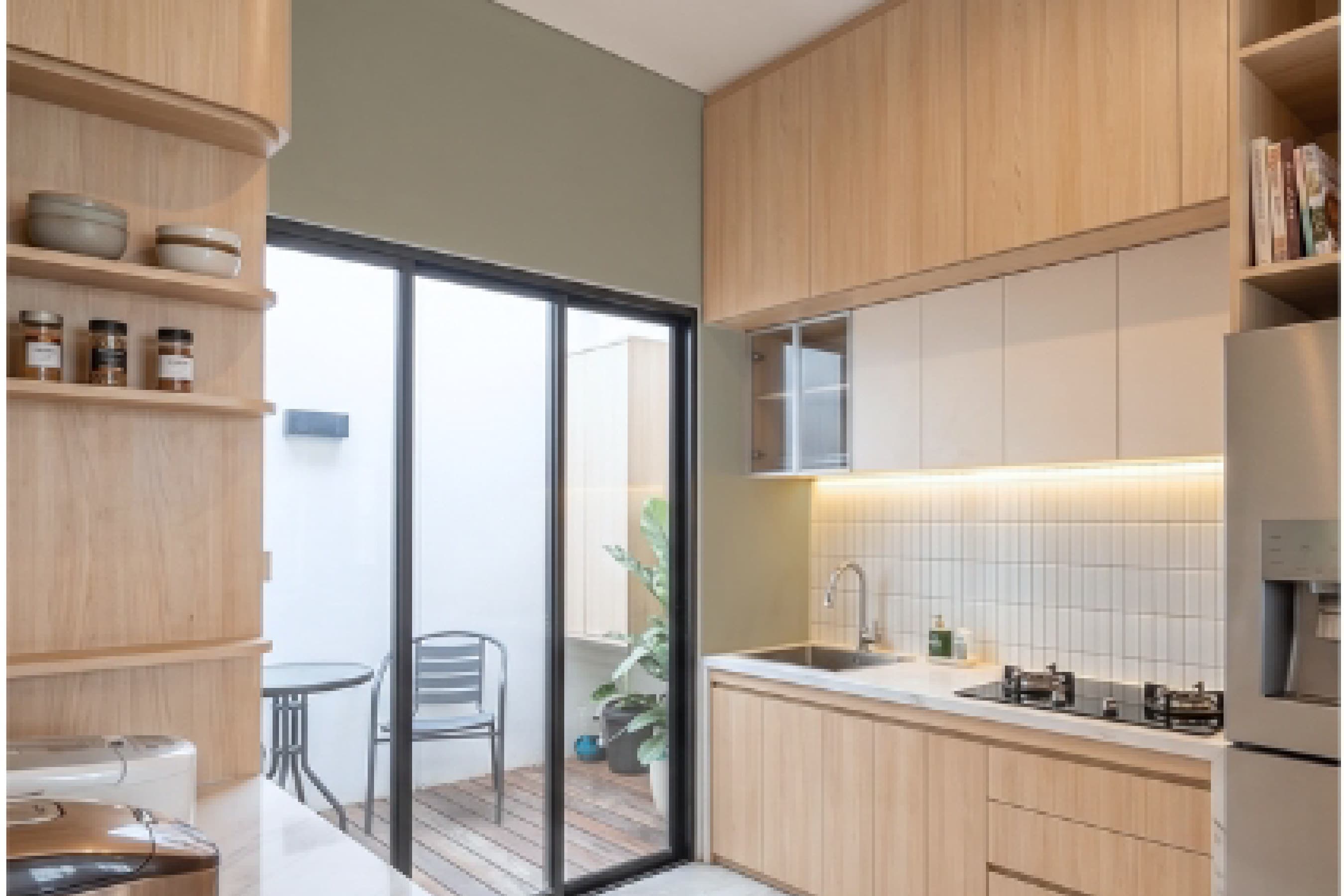 Kitchen with timber cabinetry and full-height glass doors opening onto an outdoor patio.