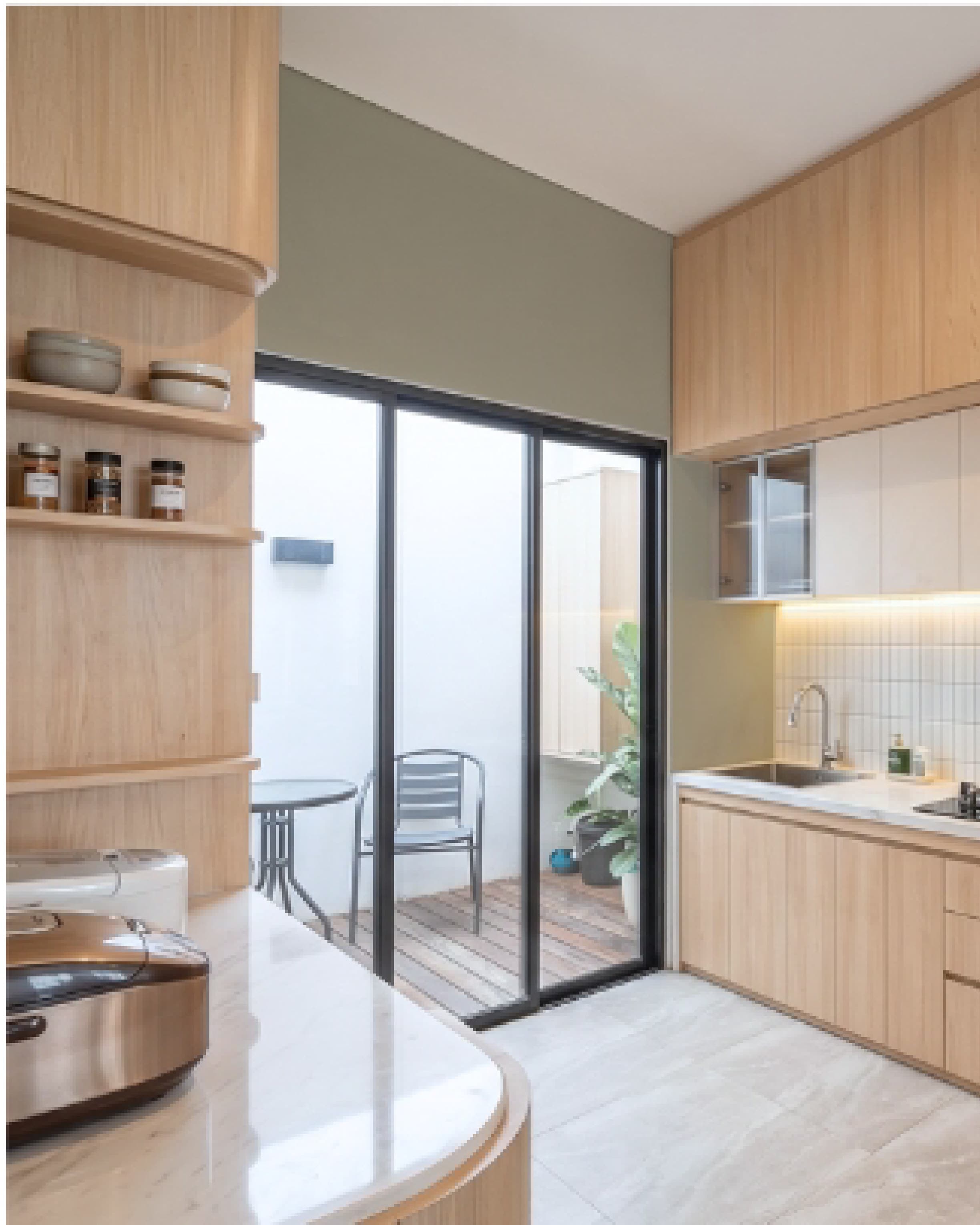 Kitchen with timber cabinetry and full-height glass doors opening onto an outdoor patio.