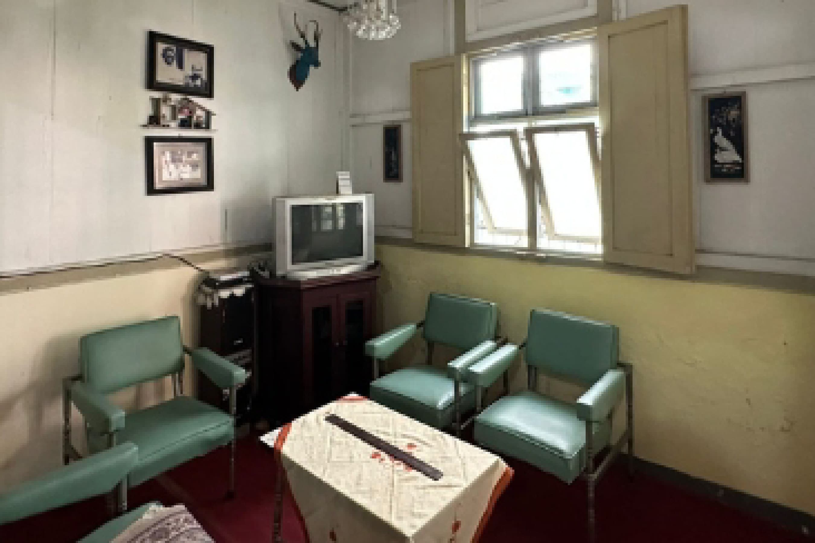 Site documentation of the existing room with teal armchairs, a vintage television and framed photographs.