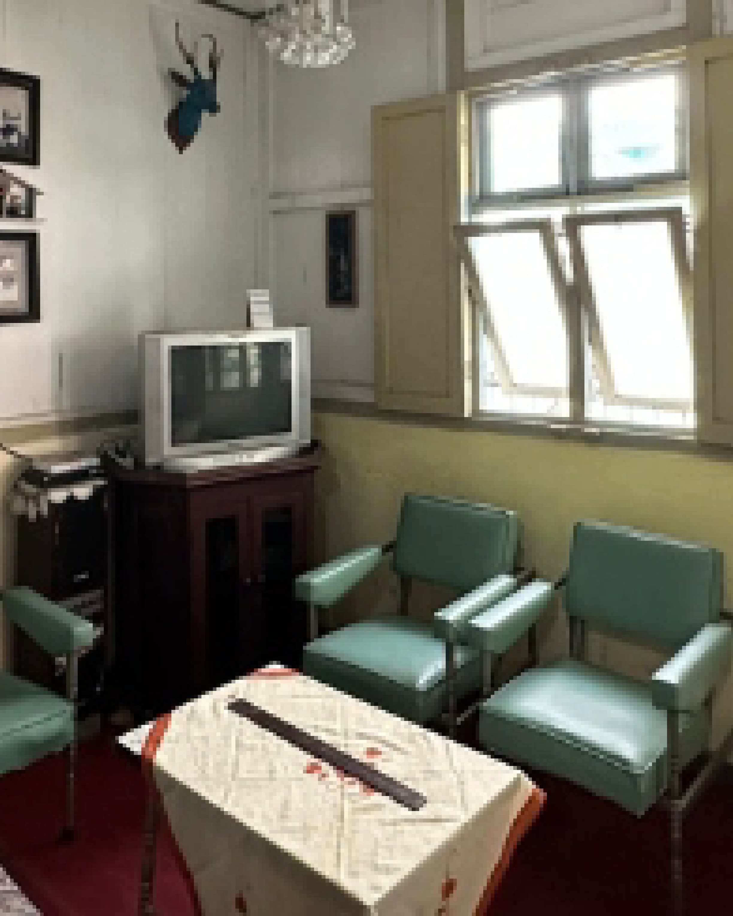 Site documentation of the existing room with teal armchairs, a vintage television and framed photographs.